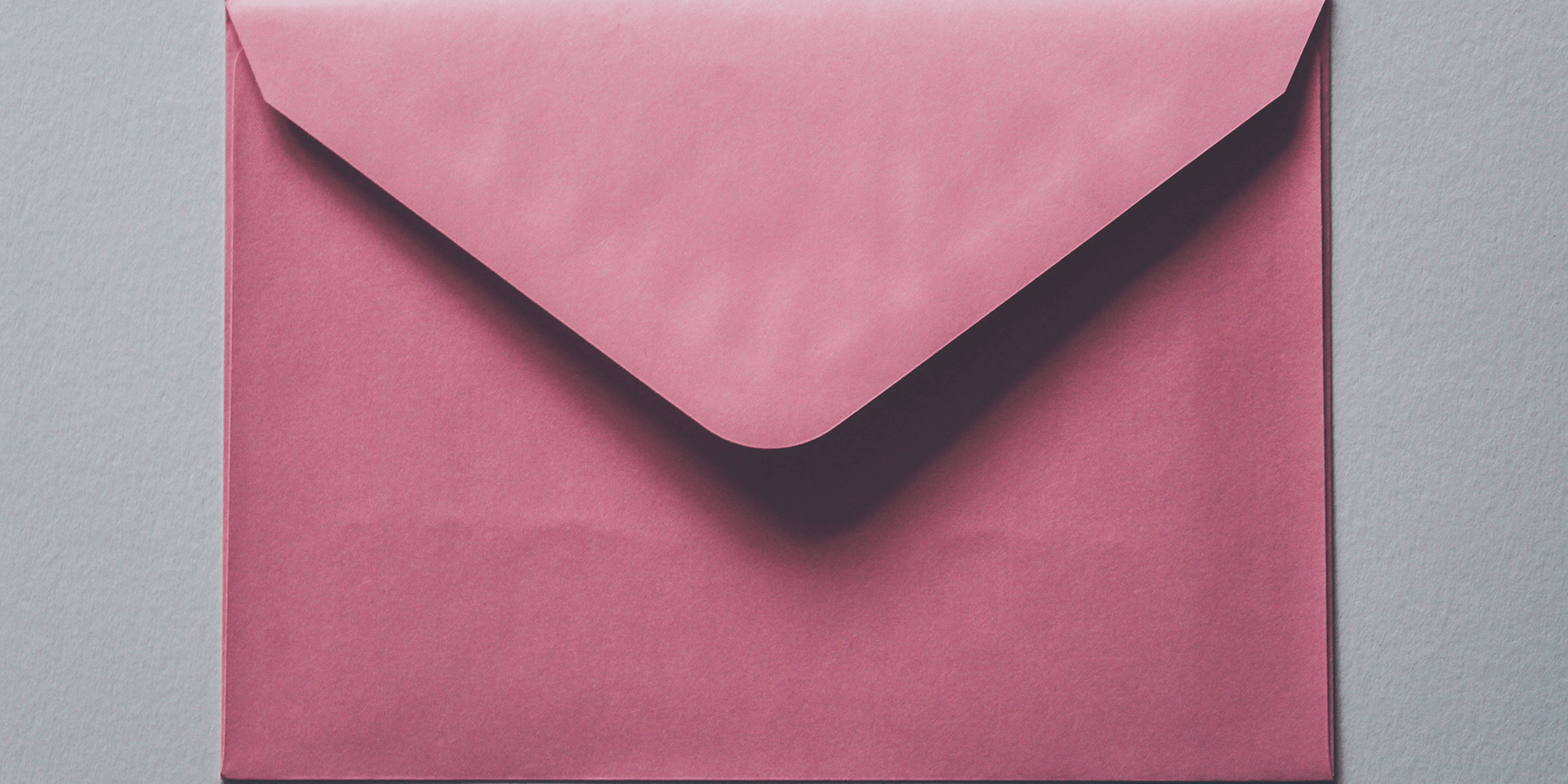 A pink envelope on a gray background.